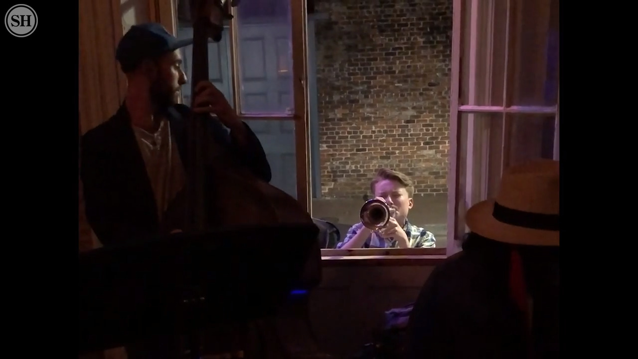 Young musician joins jazz session from outside window of New Orleans club