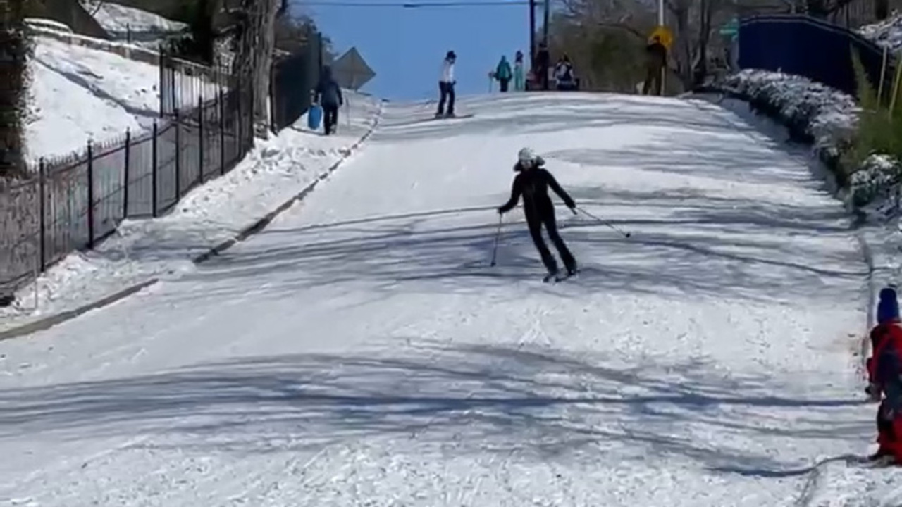 Watch people downhill ski, sled on Fort Worth road