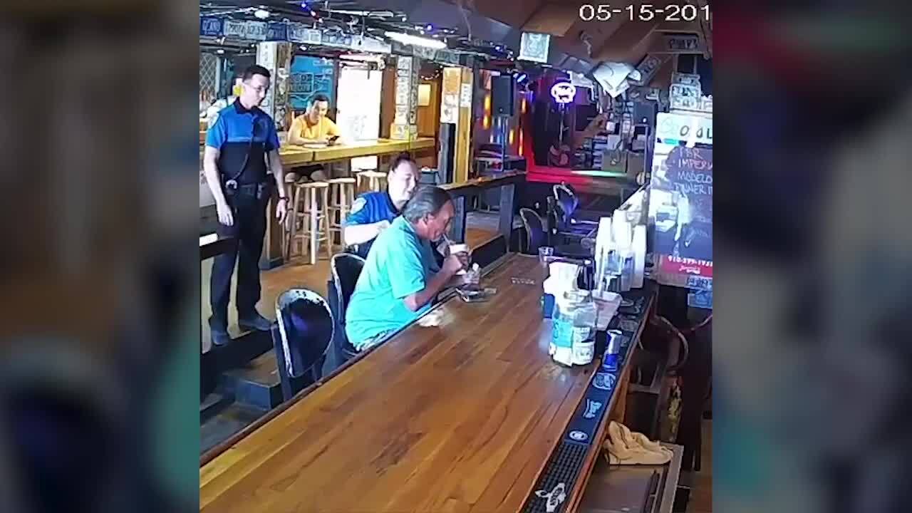 Man tries to finish drink at bar as police escort him out