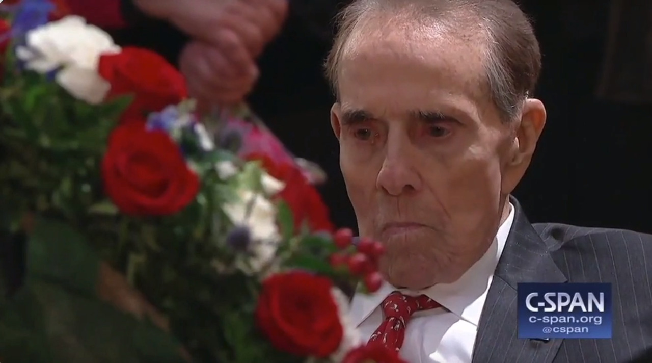 Former Kansas Sen. Bob Dole stands to salute as President George H.W. Bush lies in state