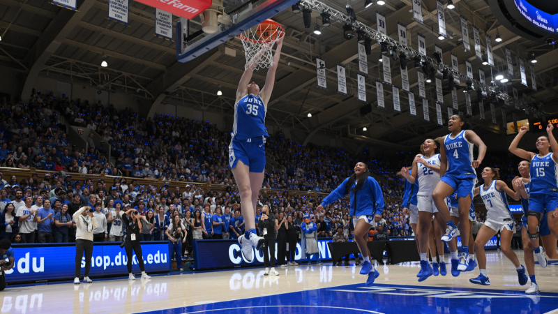 Duke women's player Toby Fournier makes a spectacular dunk and is swarmed by players from both teams