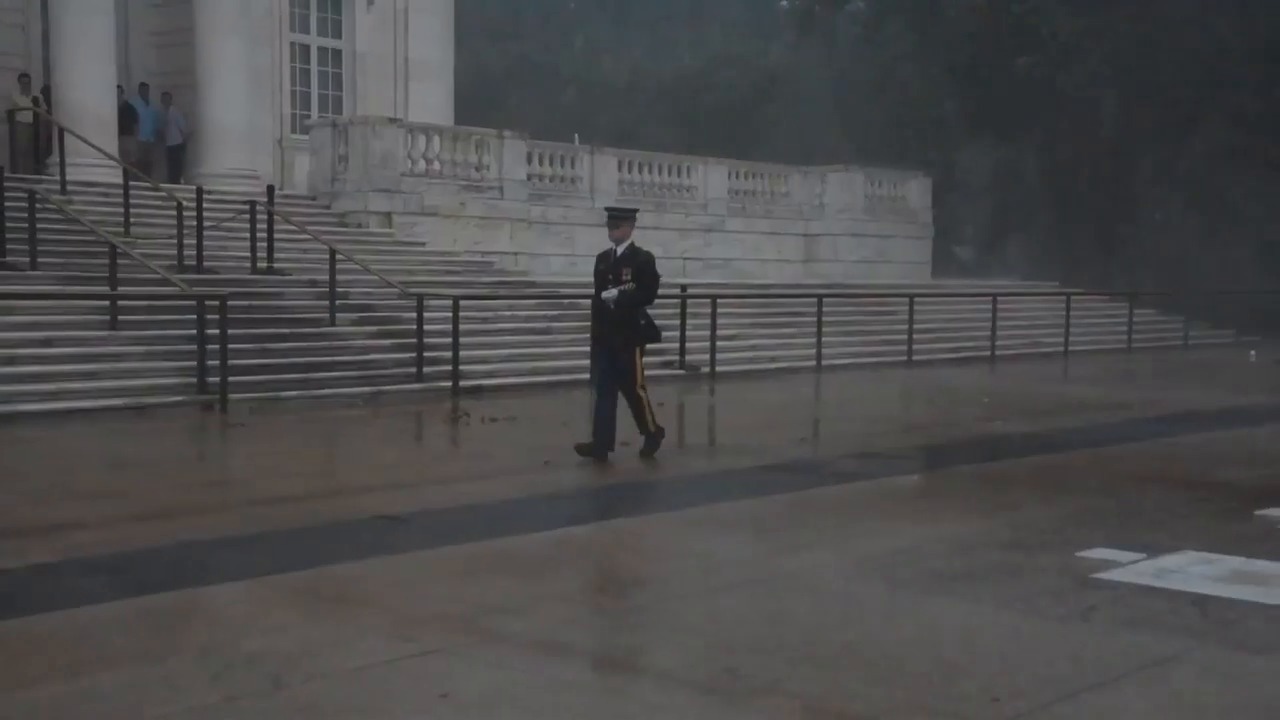 Soldier lays flag during downpour at Arlington National Cemetery