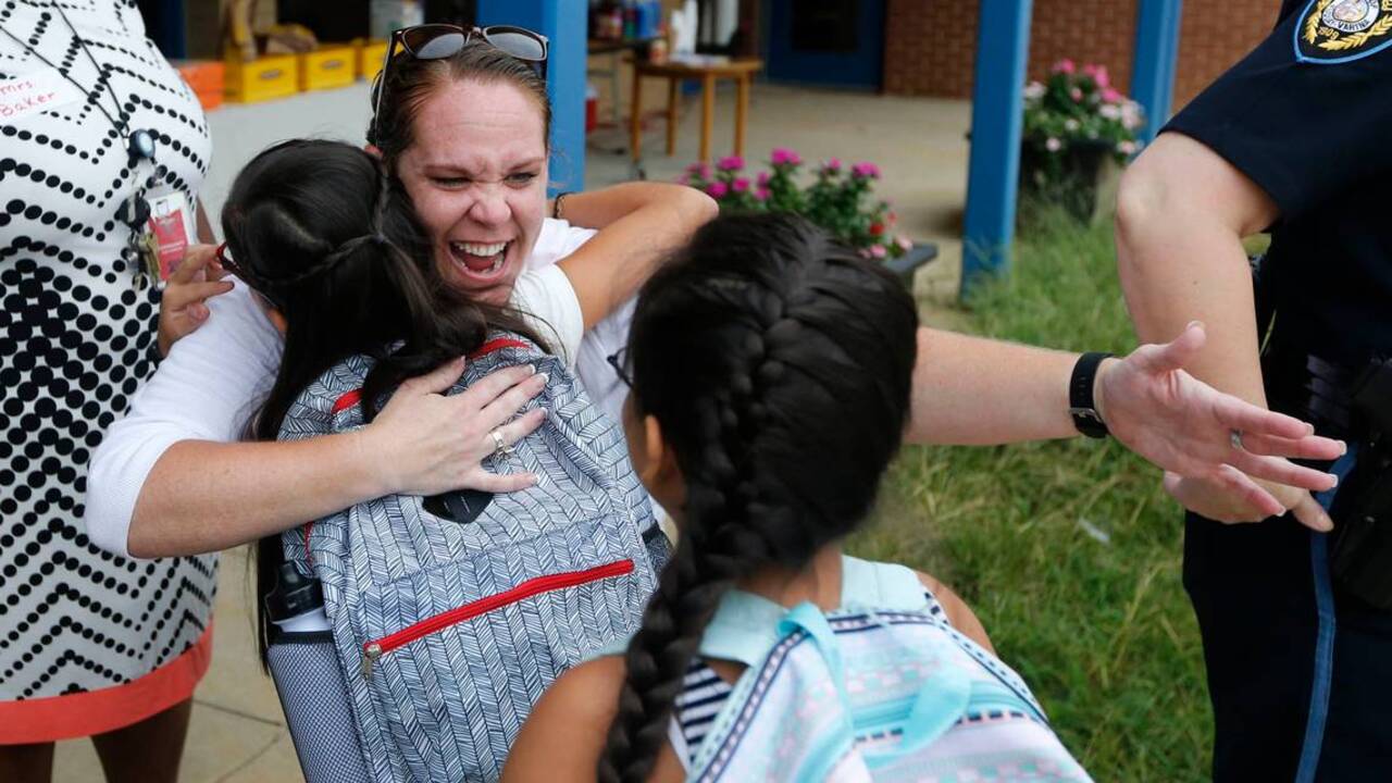 Volunteers join teachers to welcome students back to school
