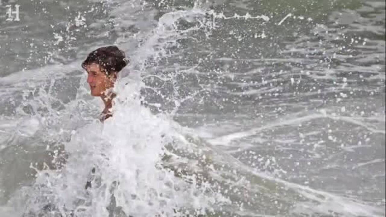 Beach goers check waves before Hurricane Matthew's arrival